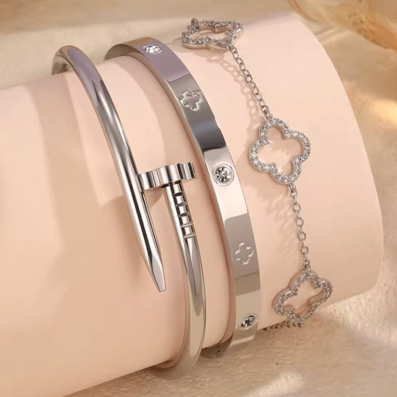 Two silver bracelets with heart-shaped charms on a beige background