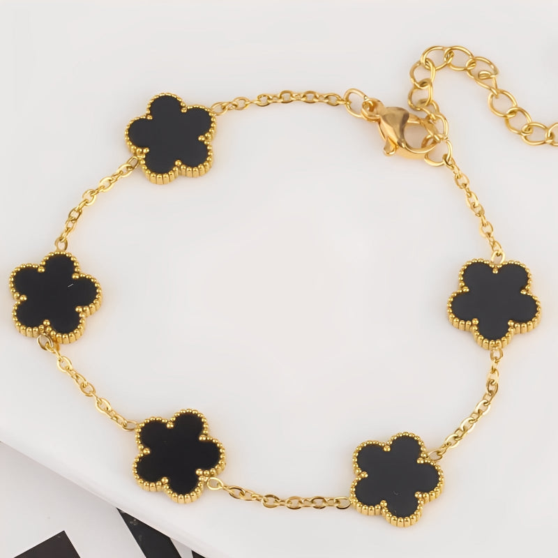 Gold bracelet with black clover-shaped charms on a white background