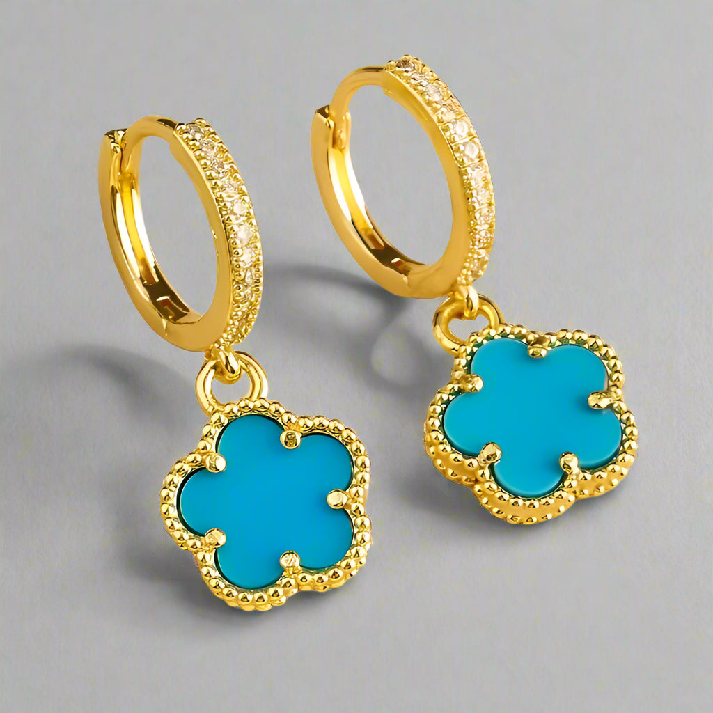 Gold hoop earrings with turquoise clover-shaped charms on a white background