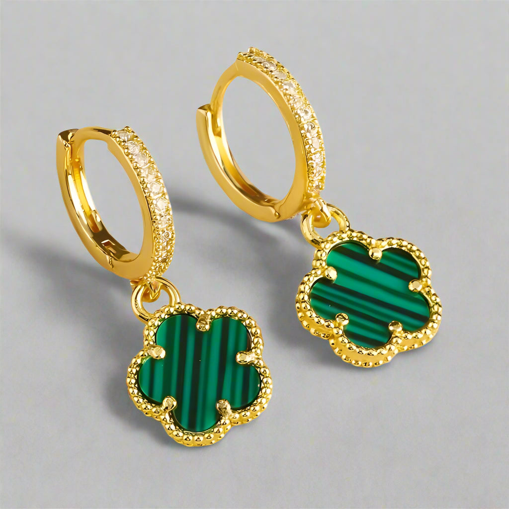 Gold hoop earrings with green stone charms on a white background