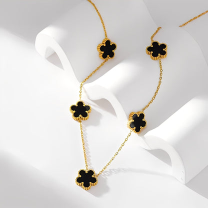 Gold necklace with black clover-shaped pendants on a white background