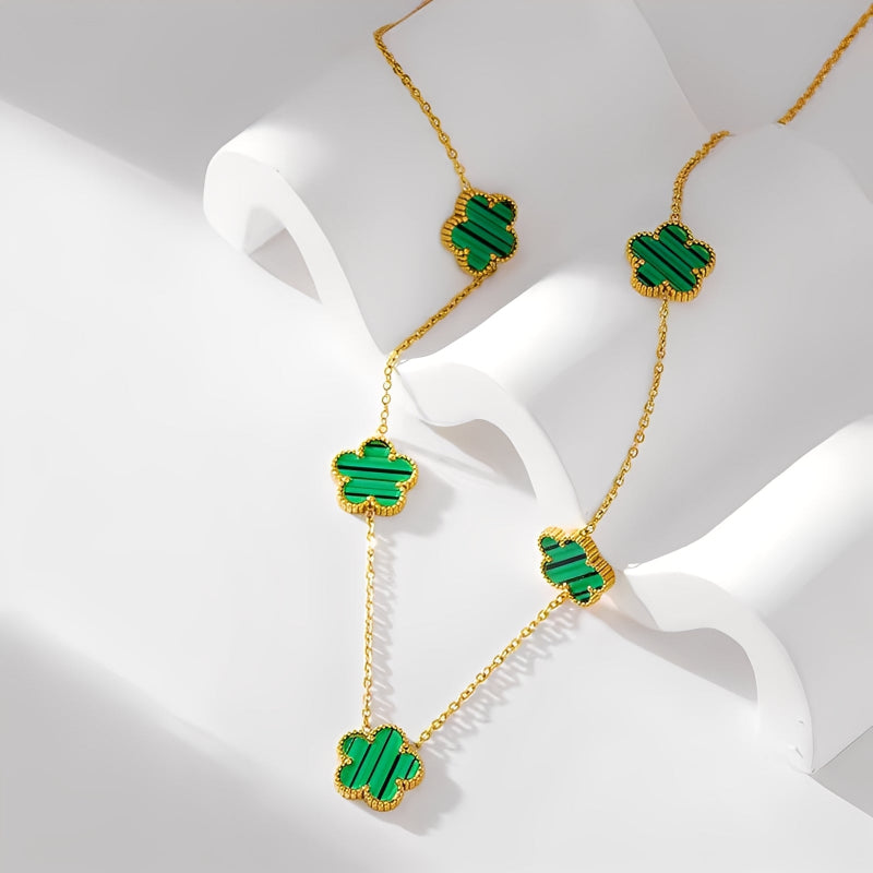Gold necklace with green gemstones on a white surface